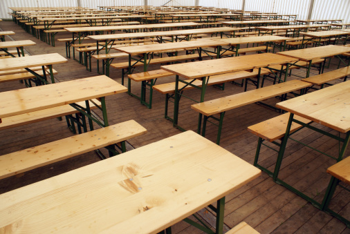 A landscape of fold-out tables wait for party-goers inside a festival tent.