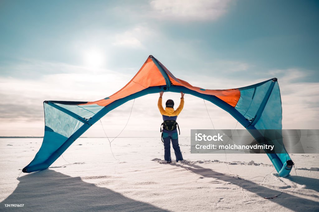 Sporty girl stands with snow kite Sporty girl stands and hold snowkite in hands. Winter kitesurfing concept Kiteboarding Stock Photo