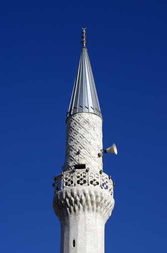 A minaret on a mosque in Prishtina, Kosovo as seen at noon on a sunny day.