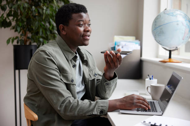 istock Enthusiastic Young Man Working From Home On Laptop Speaking Into Mic On Mobile Phone 1341903515