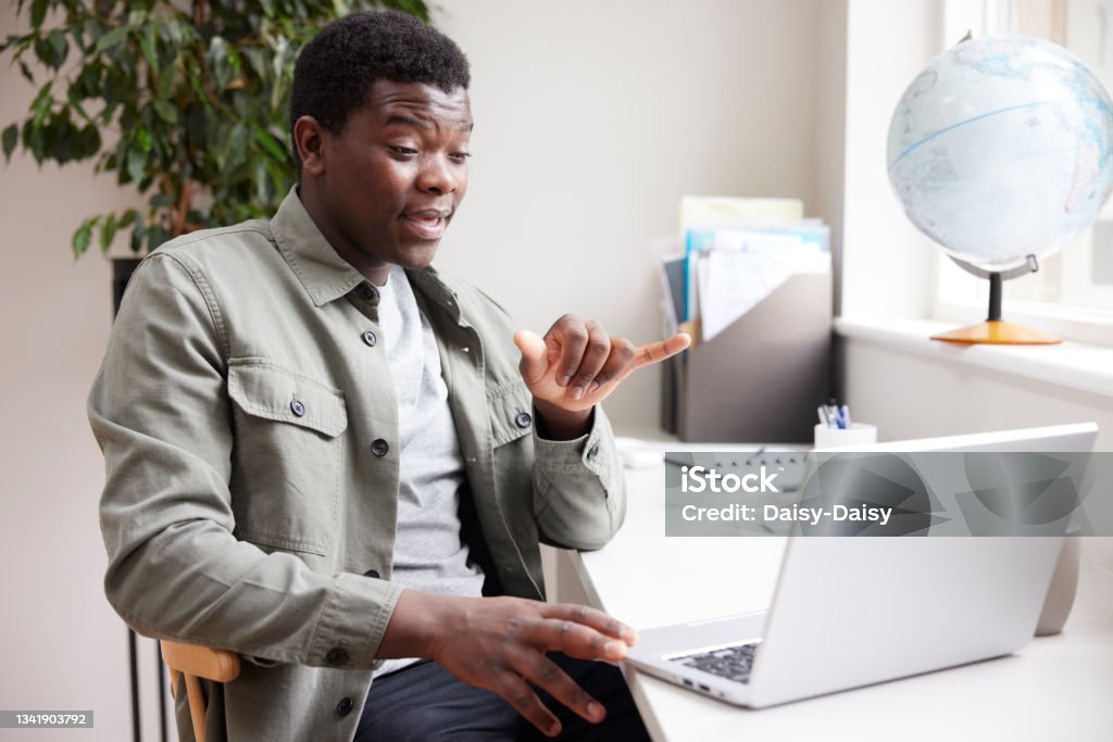 Young Man Having Conversation Using Sign Language On Laptop At Home Sign Language Stock Photo