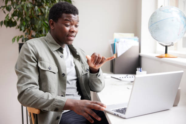 Young Man Having Conversation Using Sign Language On Laptop At Home Young Man Having Conversation Using Sign Language On Laptop At Home american sign language photos stock pictures, royalty-free photos & images