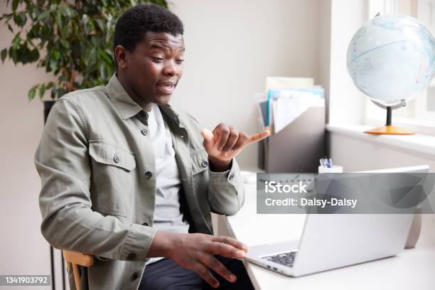 Young Man Having Conversation Using Sign Language On Laptop At Home Stock Photo - Download Image Now