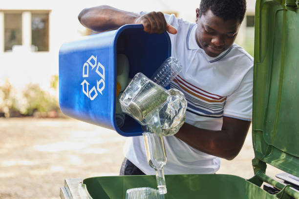 young man emptying household recycling into green bin - 循環再造 個照片及圖片檔