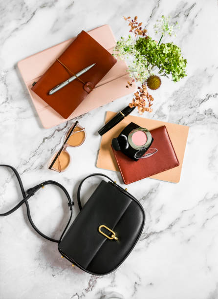 istock Women's office desktop - notebooks, organizer, tablet, cross body black leather bag on a marble background, top view 1341904462