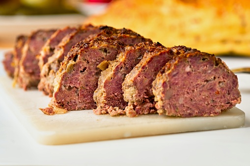 Baked sliced meatlof on kitchen board, blurred bread on background.