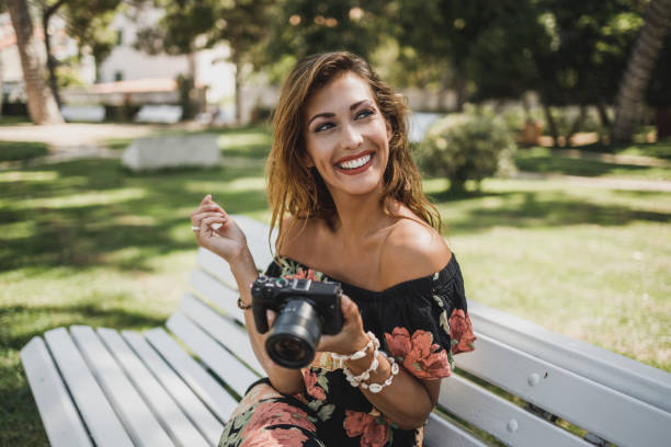 istock Woman With Digital Camera Sitting On The Bench In The Park 1341906073