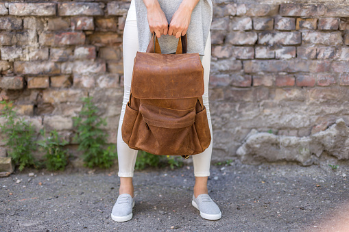 Brown leather bag in the hand on a woman. Unisex bag for sale.