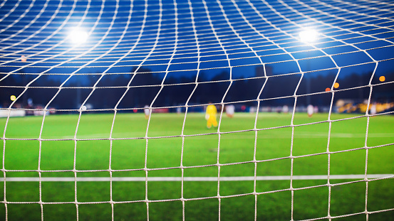 Football background - view of the field from behind the goal during a match spotlights - blurred background