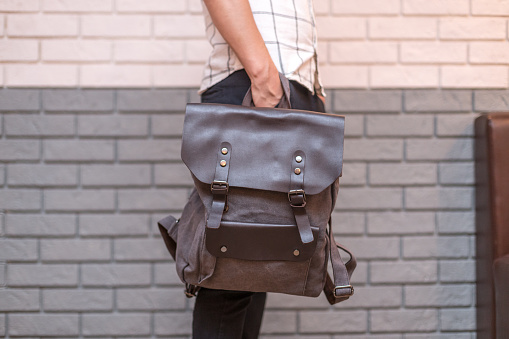 Man holding brown leather bag in the hand. Unisex bags for sale.