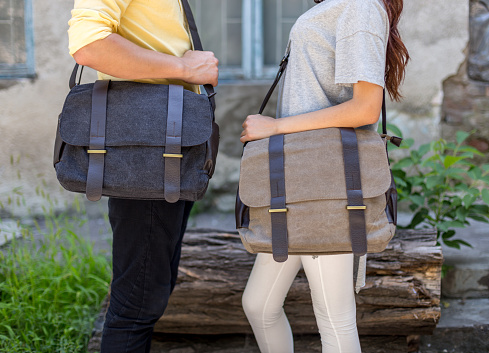 Man and woman with a gray canvas messenger bag in the hand. Unisex bag