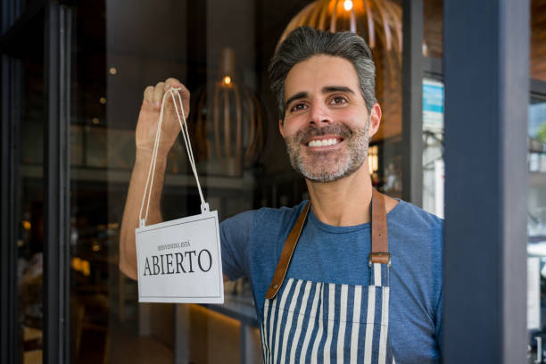 istock Happy waiter holding an open sign in Spanish at a restaurant 1341912065