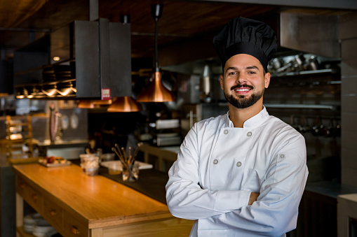 Portrait of a successful Latin American chef working at a restaurant and looking at the camera with arms crossed