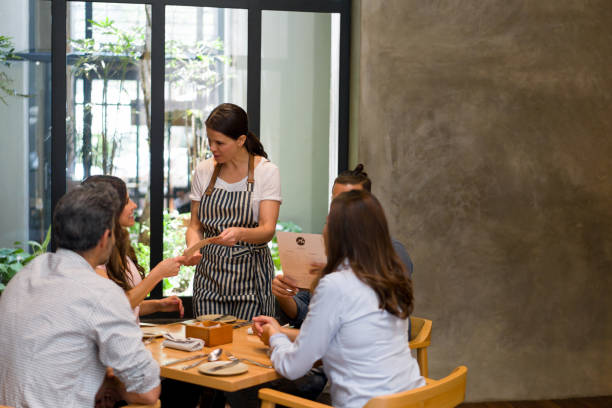 istock Waitress serving a group of people at a restaurant 1341912110
