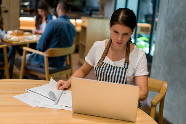 istock Manager working at a restaurant doing the books on a laptop 1341912111