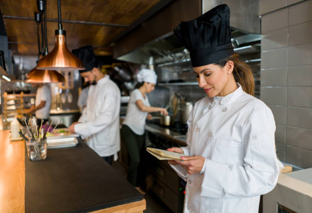 istock Chef working at a restaurant and reading a recipe on a notepad 1341912141