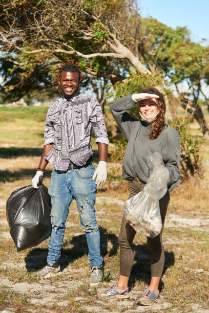 istock Diverse young friends smiling while collecting garbage outside during a community cleanup 1341912229