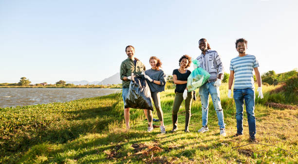 istock Diverse volunteers smiling while collecting litter in a nature reserve by a river 1341913033