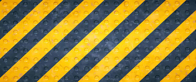 Front view close-up of a studded surface grid floor painted in yellow and black colors. Wide horizontal composition.