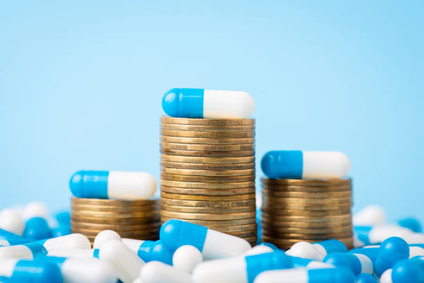 Stacks of coins between medical pills capsules stock photo