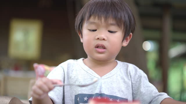 Toddler boy eating cake in a cake shop by himself