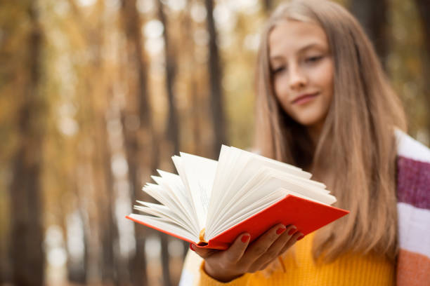 istock Young girl reading book in autumn park 1341916906