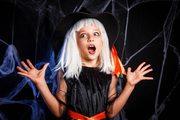 Little girl in witch costume having fun on Halloween trick or treat stock photo