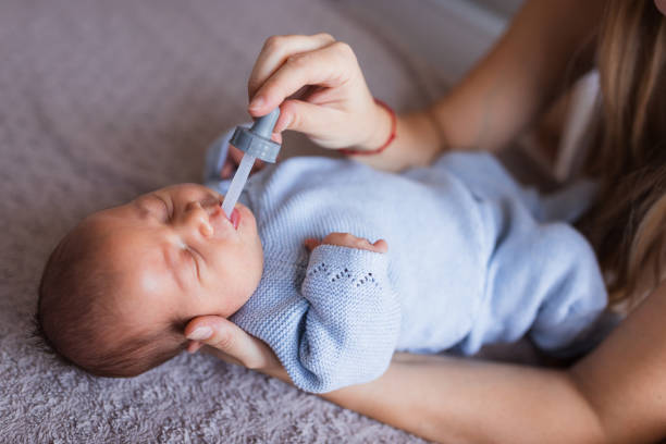 Mother feeding newborn baby boy through pipette
