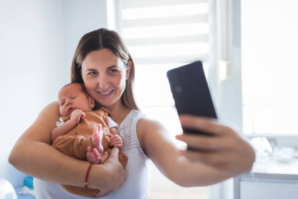 Happy woman taking a selfie with her newborn son