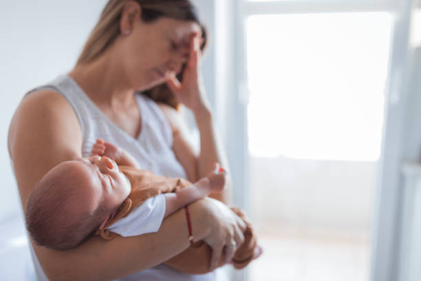 Woman having headache when holding a baby Woman putting baby to sleep while having a severe head pain legacy concept photos stock pictures, royalty-free photos & images