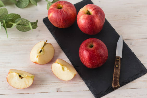 istock In a rectangular black slate dish on white wooden table are three juicy beautiful ripe red apples of the early winter variety Gala. Next to the slices of the cut fruit and a knife. Top view 1341923343