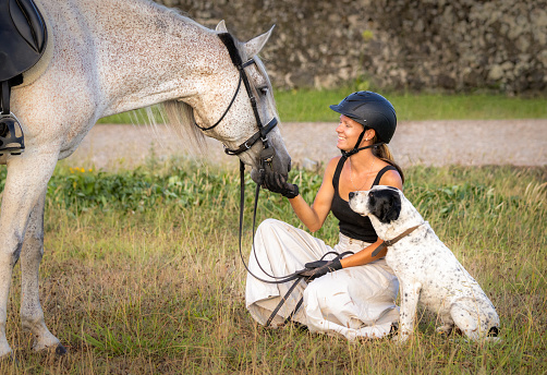 Dressage rider, with horse and dog outdoors, having a great time.