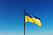 Die Flagge der Ukraine entwickelt sich auf einem Fahnenmast vor dem Hintergrund des klaren Himmels