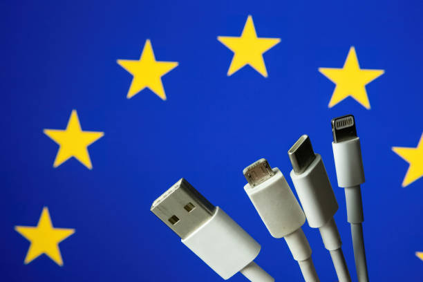 EU flag and different charging cables such as USB, USB-C, Micro USB, lightning cable. stock photo