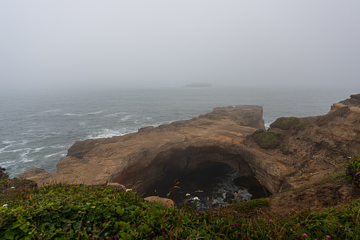 Geological formations and moody atmospheric conditions at Devils Punch Bowl on the Oregon Coast, Pacific Northwest