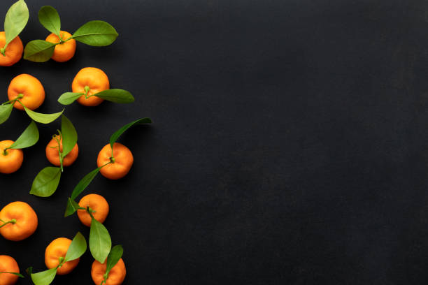 istock Clementines with leaves on a black background. Top view with copy space. 1341934577