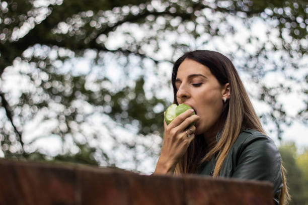 istock Cheerful young woman eating an apple 1341937147