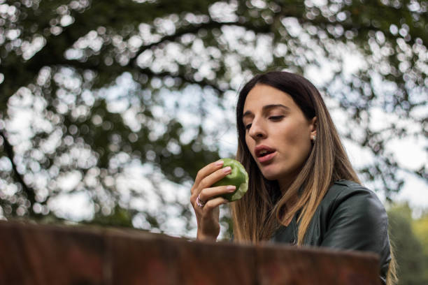 istock Cheerful young woman eating an apple 1341937172