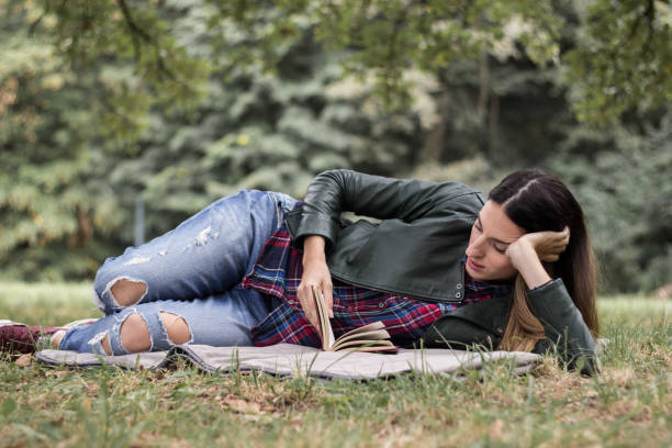 istock Woman reading a book while laying on the grass 1341937812