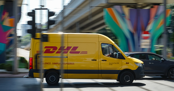 Bucharest, Romania - August 11, 2021 An yellow DHL delivery speeding through the traffic in Bucharest. This image is for editorial use only.