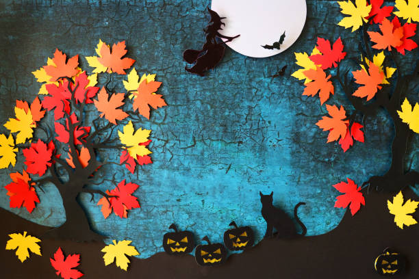 Stock photo showing a Halloween night scene poster / background design with homemade cut out full moon, bats, cat, pumpkin Jack O'lanterns, witch flying on broomstick and tree shapes covered with red, orange and yellow maple leaves on cracked blue background.