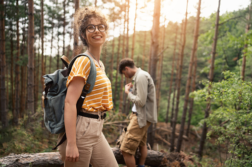 Cheerful young Caucasian couple hiking in the forest together. Traveling concept. Focus on a young woman.