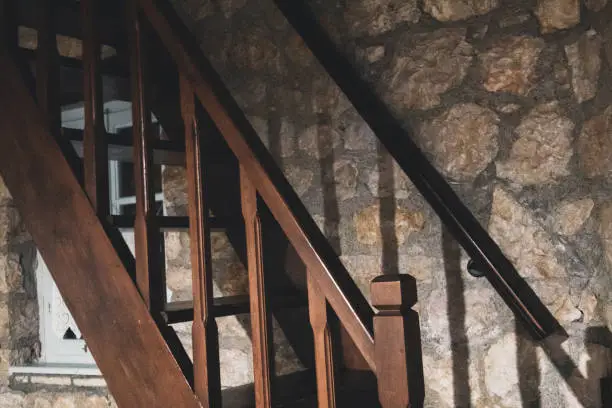 Photo of Wooden stairs with stones wall in old Greek house