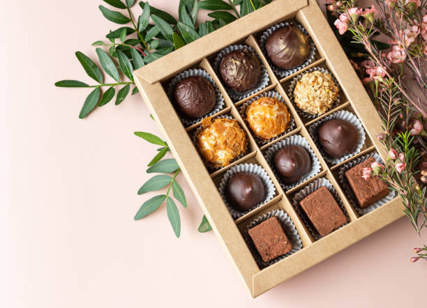 istock Gift craft box with assorted chocolates and pink flowers on a light concrete background. Top view. 1341946157