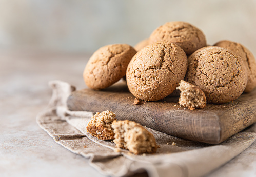 Oatmeal cookies on wooden cutting board, brown concrete background. Healthy snack or dessert. Selective focus.