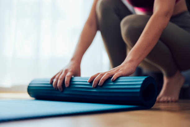 istock An Anonymous Woman Folding Blue Exercise Mat on Wooden Floor 1341947326