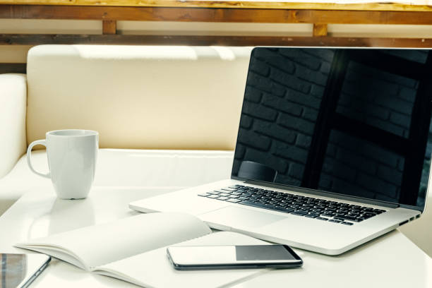 istock Open laptop on table near sofa, home interior. Freelancer workplace concept 1341951218