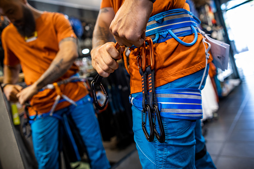 Close up on males hands fixing the harness in an outdoor store during mountaineering equipment  shopping for new adventures.