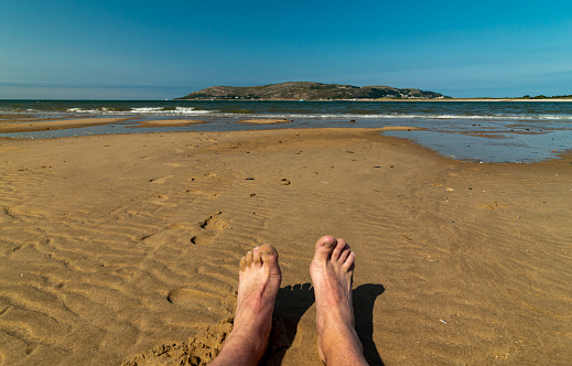 Feet and legs of a man resting during vacation by the sea. Pov