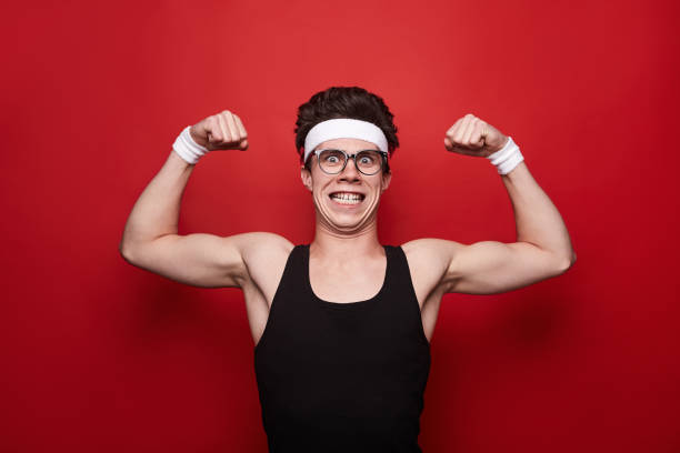 istock Funny man showing biceps on red background 1341962086